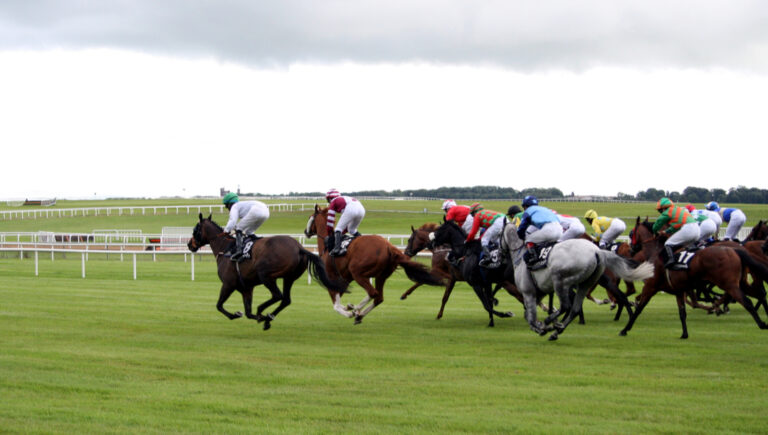 Jockeys on horses racing around the green track.
