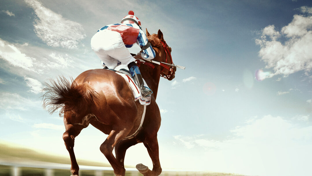 A jockey on a horse racing with clouds in the background.n the world.