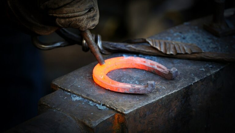 A blacksmith kicks a horseshoe.