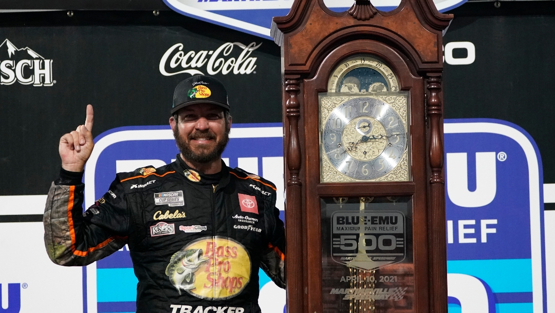 Martin Truex Jr. (19) celebrates with the winners' trophy after winning the NASCAR Cup Series auto race at Martinsville Speedway in Martinsville, Va., Sunday, April 11, 2021. (AP Photo/Steve Helber)