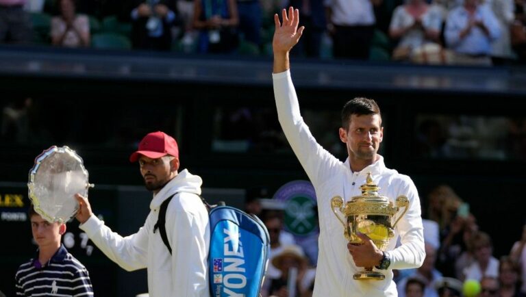 Serbia's Novak Djokovic, right, holds the winners trophy as he celebrates after beating Australia's Nick Kyrgios, left, to win the final of the men's singles on day fourteen of the Wimbledon tennis championships in London, Sunday, July 10, 2022.