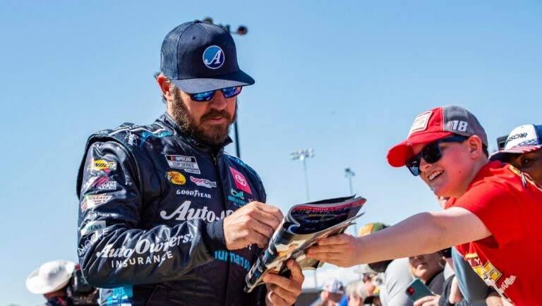 Martin Truex Jr. signs an autograph at a NASCAR Cup Series auto race at Richmond Raceway on Sunday, April 3, 2022, in Richmond, Va. (AP Photo/Mike Caudill)