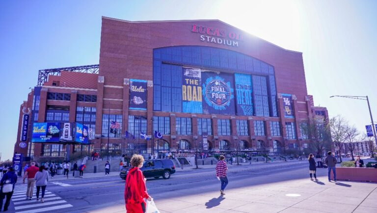 FILE - Fans pose with a Final Four logo before a college basketball game during the Final Four round of the NCAA tournament at Lucas Oil Stadium in Indianapolis, in this Saturday, April 3, 2021, file photo. A law firm hired to investigate gender equity concerns at NCAA championship events released a blistering report Tuesday, Aug. 3, 2021, that recommended holding the men's and women's Final Fours at the same site and offering financial incentives to schools to improve their women's basketball programs.