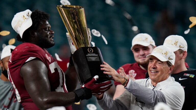 Alabama head coach Nick Saban and offensive lineman Alex Leatherwood hold the trophy after their win against Ohio State in an NCAA College Football Playoff national championship game, Tuesday, Jan. 12, 2021, in Miami Gardens, Fla. Alabama won 52-24. (AP Photo/Chris O'Meara)