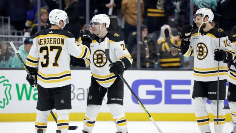 Boston Bruins from left, center Patrice Bergeron (37), left wing Jake DeBrusk (74), and left wing A.J. Greer (10) celebrate the 6-5 win over the Seattle Kraken of an NHL hockey game, Thursday, Feb. 23, 2023, in Seattle.