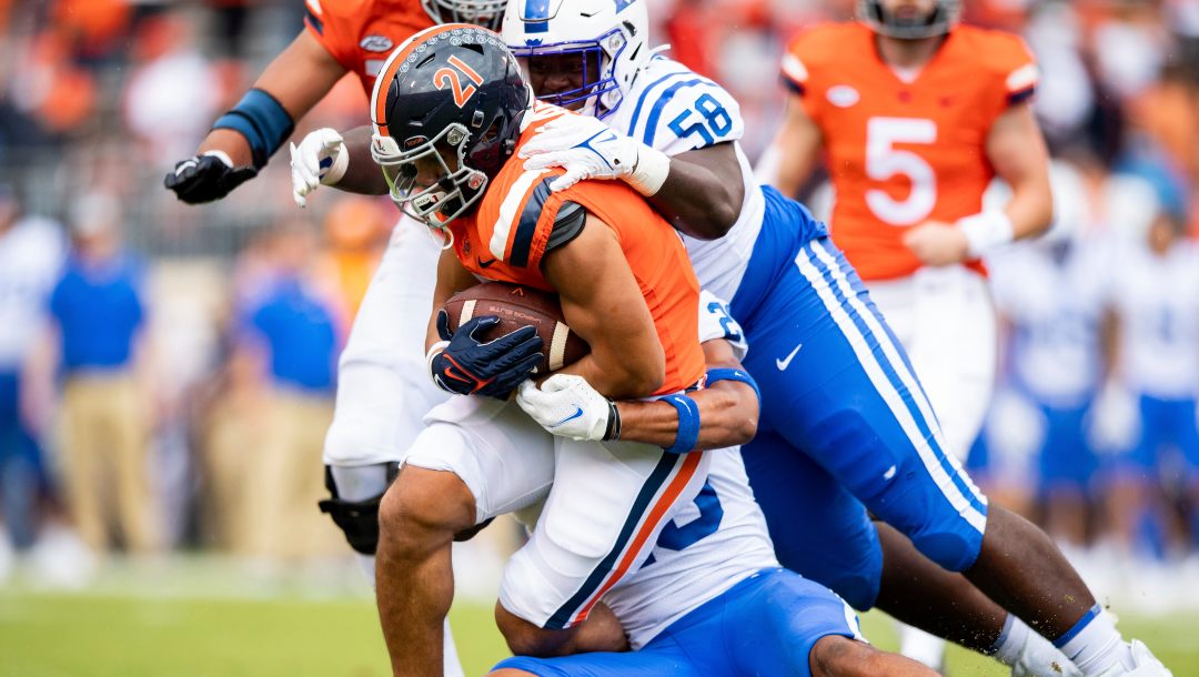 Virginia tailback Wayne Taulapapa (21) is tackled by Duke defensive tackle Gary Smith III (58) and safety Lummie Young IV (23) during the first quarter of an NCAA college football game at Scott Stadium on Saturday, Oct. 16, 2021, in Charlottesville, Va.