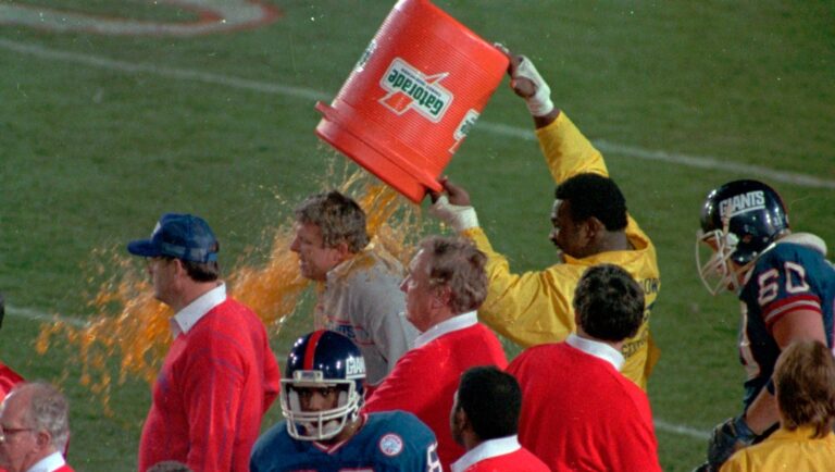 Wearing a Rose Bowl security jacket, New York Giants Harry Carson dumps a bucket of Gatorade on coach Bill Parcells toward the end of Super Bowl XXI against the Denver Broncos, Jan.25, 1987. Giants won, 39-20. (AP Photo/Douglas C. Pizac)