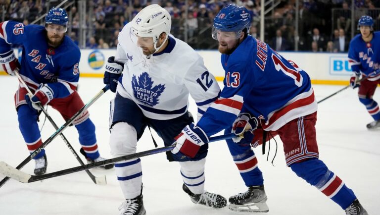 Toronto Maple Leafs center Zach Aston-Reese (12) and New York Rangers left wing Alexis Lafrenière (13) battle for the puck during the third period of an NHL hockey game, Thursday, April 13, 2023, in New York. (AP Photo/John Minchillo)