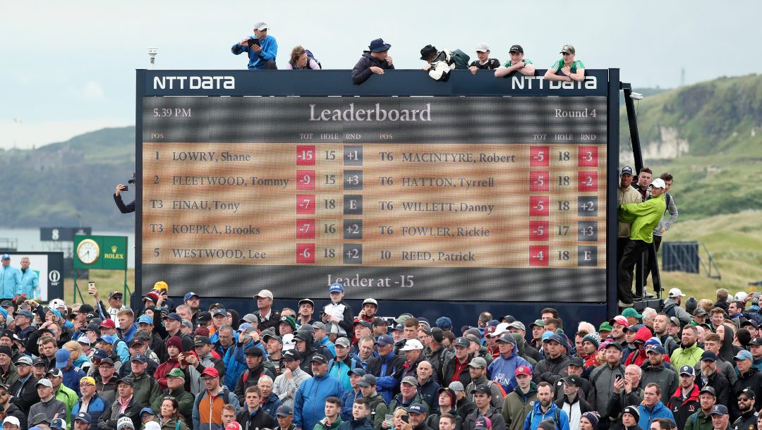 Spectators clamber on to and on top of a scoreboard as they vie to get a glimpse of Ireland's Shane Lowry and England's Tommy Fleetwood as they play during the final round of the British Open Golf Championships at Royal Portrush in Northern Ireland, Sunday, July 21, 2019.