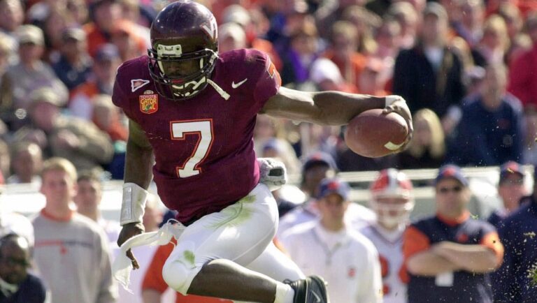 In this Jan. 1, 2001, file photo, Virginia Tech quarterback Michael Vick (7) eludes Clemson's Keith Adams for a short gain in the first quarter of the Gator Bowl NCAA college football game in Jacksonville, Fla. Public opposition is growing against the planned induction of former football star Michael Vick into the Virginia Tech Sports Hall of Fame. The Roanoke Times reported that two online petitions at change.org had received more than 90,000 combined signatures against the September induction.