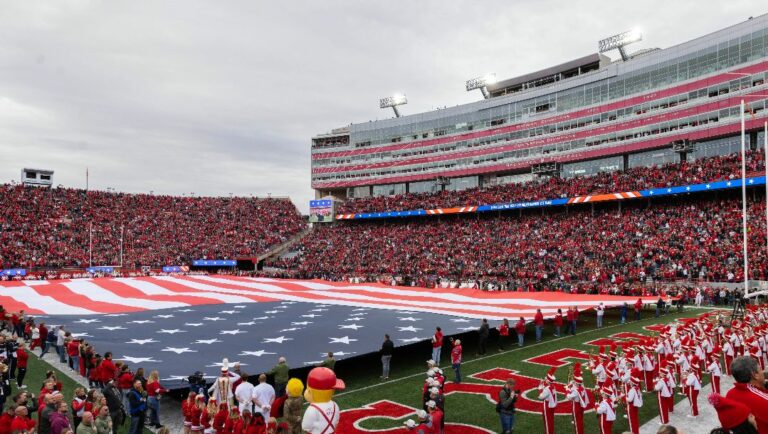 An American flag fills the field during the singing of the national anthem before Maryland and Nebraska play in an NCAA college football game Saturday, Nov. 11, 2023, in Lincoln, Neb.