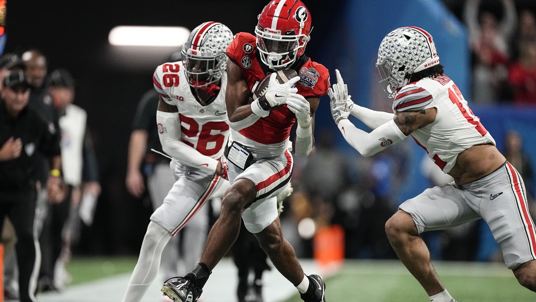 Georgia wide receiver Adonai Mitchell, center, makes a catch against Ohio State cornerback Cameron Brown (26) during the first half of the Peach Bowl NCAA college football semifinal playoff game Dec. 31, 2022, in Atlanta. Texas receiver Adonai Mitchell could have stayed at Georgia where he was already a hero. He had two of the biggest catches in program history in help the Bulldogs to the last two national championships. But the coos and cuddles of a toddler daughter drew him home to Texas.