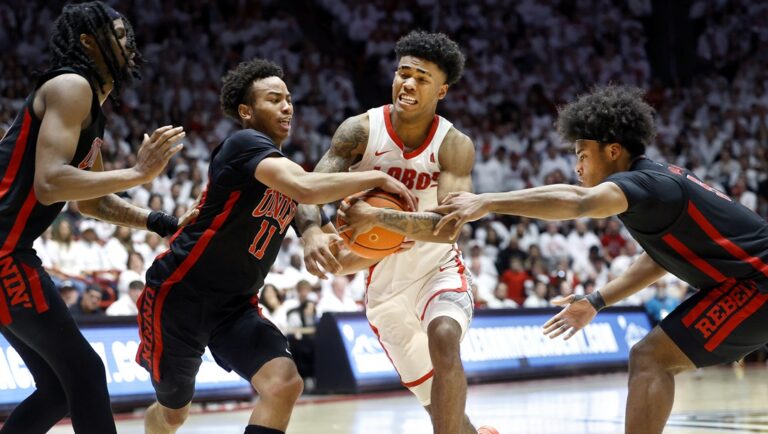 New Mexico guard Donovan Dent tries to drive between UNLV defenders, from left, Deraje Agbaosi, Dedan Thomas Jr. and Rob Whaley Jr. during the second half of an NCAA college basketball game, Saturday, Feb. 10, 2024, in Albuquerque, N.M.