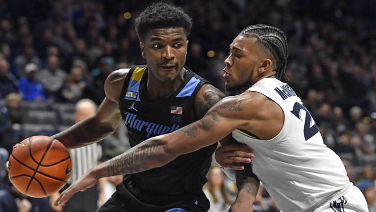 Xavier guard Dayvion McKnight (20) attempts to tip the ball away from Marquette guard Kam Jones (1) during the second half of an NCAA college basketball game in Cincinnati, Saturday, March 9, 2024. Marquette won 86-80.