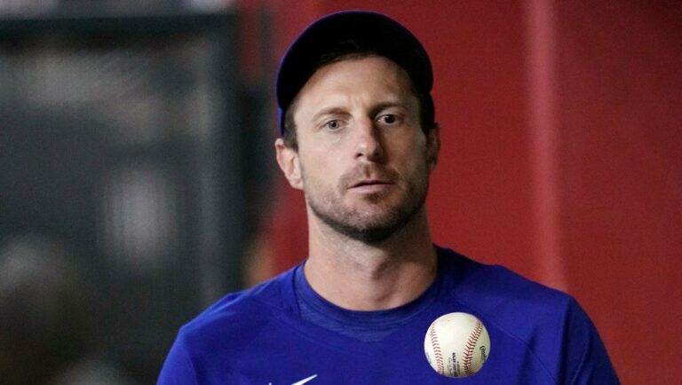 FILE- Texas Rangers' Max Scherzer flips the ball in the air as he paces the dugout during the seventh inning of a baseball game against the Arizona Diamondbacks Tuesday, Aug. 22, 2023, in Phoenix. Scherzer logged at least 179 innings in 10 of his first 16 years in the majors. And the three-time Cy Young Award winner learned some tough lessons on the road to pitching deep into games. That's one reason why the Rangers right-hander thinks Major League Baseball needs to look a lot deeper than a roster limit if it wants to return starting pitching to prominence. (AP Photo/Ross D. Franklin, File)