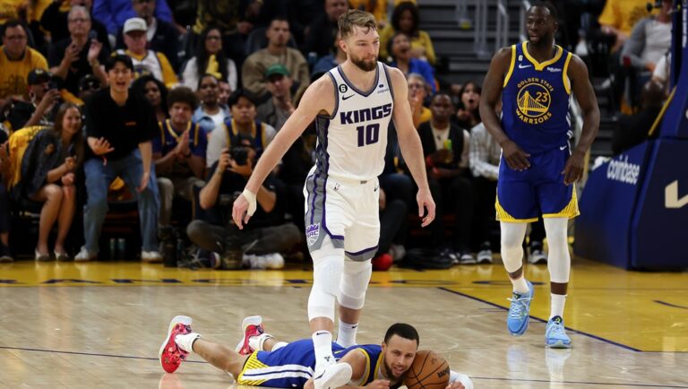 Domantas Sabonis #10 of the Sacramento Kings steps over Stephen Curry #30 of the Golden State Warriors after Sabonis fouled Curry in the second half of Game Six of the Western Conference First Round Playoffs at Chase Center on April 28, 2023 in San Francisco, California.