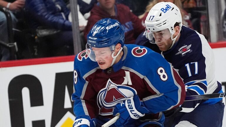 Colorado Avalanche defenseman Cale Makar, left, collects the puck with Winnipeg Jets center Adam Lowry, right, in pursuit in the second period of Game 4 of an NHL Stanley Cup first-round playoff series Sunday, April 28, 2024, in Denver. (AP Photo/David Zalubowski)