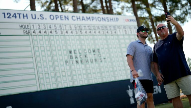 Fans pose near the main leaderboard during a practice round for the U.S. Open golf tournament Wednesday, June 12, 2024, in Pinehurst, N.C.
