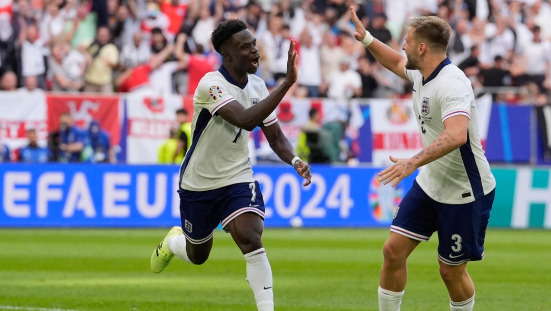 England's Bukayo Saka, left, is congratulated by Luke Shaw after scoring his side's first goal during a quarterfinal match between England and Switzerland at the Euro 2024 soccer tournament in Duesseldorf, Germany, Saturday, July 6, 2024.