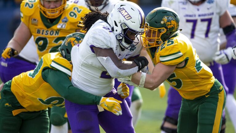 James Madison running back Latrele Palmer (21) is tackled by North Dakota State safety Michael Tutsie (25) and defensive end Tony Pierce (90) during the second half of the FCS championship NCAA college football game, Saturday, Jan. 11, 2020, in Frisco, Texas.