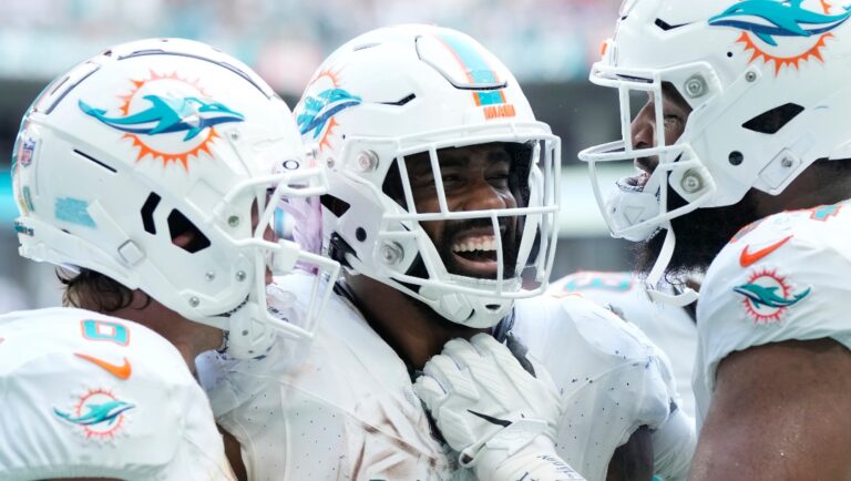 Miami Dolphins running back Raheem Mostert (31) is congratulated by wide receiver Braxton Berrios (0) and defensive tackle Christian Wilkins (94) after scoring a touchdown during the second half of an NFL football game against the Denver Broncos, Sunday, Sept. 24, 2023, in Miami Gardens, Fla. (AP Photo/Rebecca Blackwell)