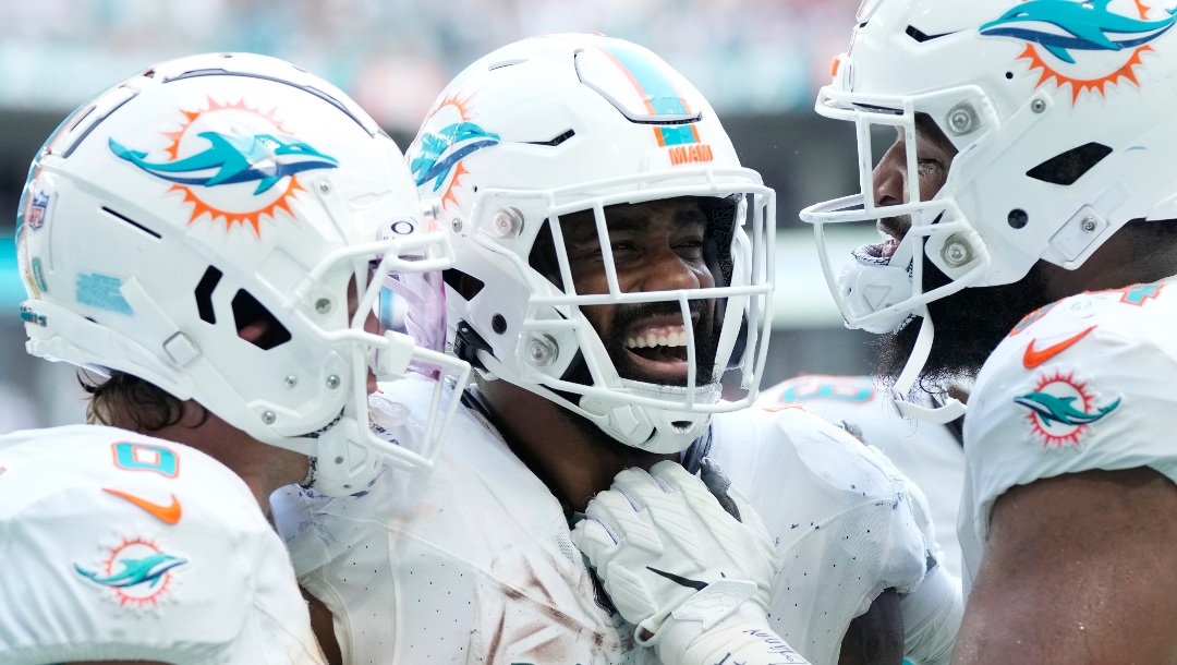 Miami Dolphins running back Raheem Mostert (31) is congratulated by wide receiver Braxton Berrios (0) and defensive tackle Christian Wilkins (94) after scoring a touchdown during the second half of an NFL football game against the Denver Broncos, Sunday, Sept. 24, 2023, in Miami Gardens, Fla. (AP Photo/Rebecca Blackwell)