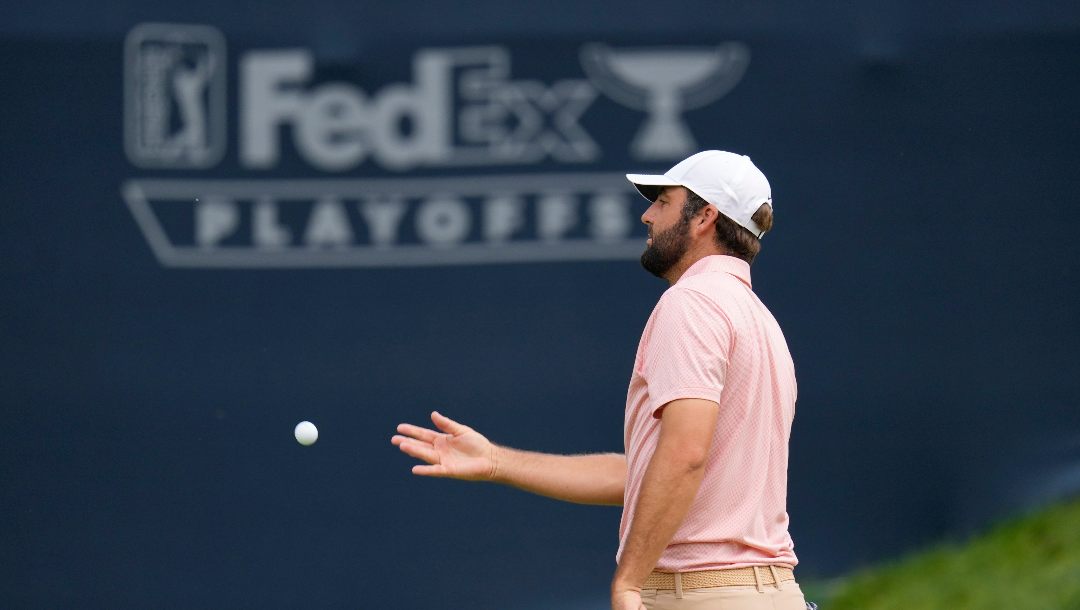 Scottie Scheffler tosses ball to his caddie after putting out on the 11th hole during the second round of the BMW Championship golf event at Castle Pines Golf Club, Friday, Aug. 23, 2024, in Castle Rock, Colo.