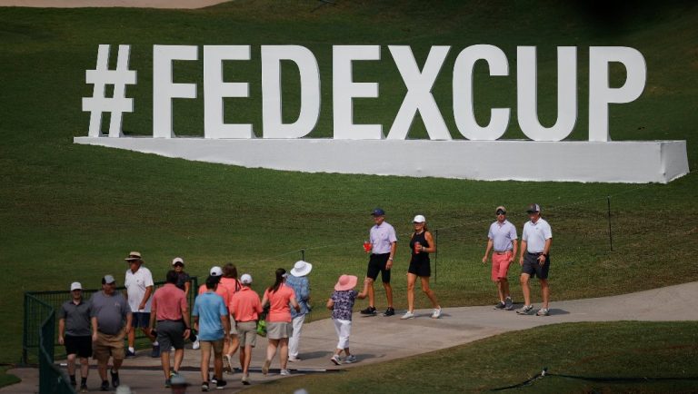 Spectators walk past cup signage during the first round of the Tour Championship golf tournament at East Lake Golf Club, Thursday, Aug. 24, 2023, in Atlanta.