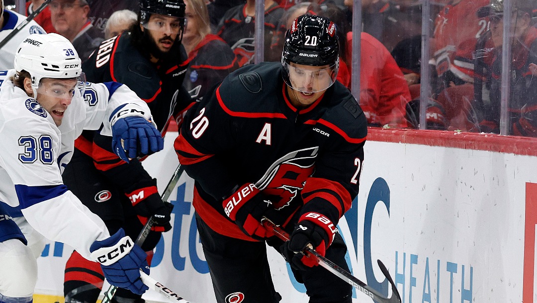 Carolina Hurricanes' Sebastian Aho (20) and Tampa Bay Lightning's Brandon Hagel (38) battle for the puck during the first period of an NHL hockey game in Raleigh, N.C., Friday, Oct. 11, 2024. (AP Photo/Karl B DeBlaker)