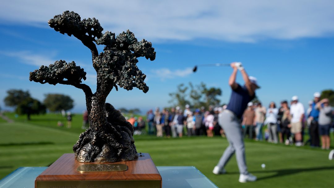 Luke List hits his tee shot on the first hole of the Sorth Course at Torrey Pines during the third round of the Farmers Insurance Open golf tournament as the tournament trophy sits on a table, left, Friday, Jan. 26, 2024, in San Diego.