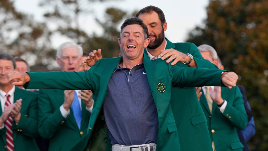Scottie Scheffler puts the green Jacket on winner, Rory McIlroy, of Northern Ireland, at the Masters golf tournament, Sunday, April 13, 2025, in Augusta, Ga.