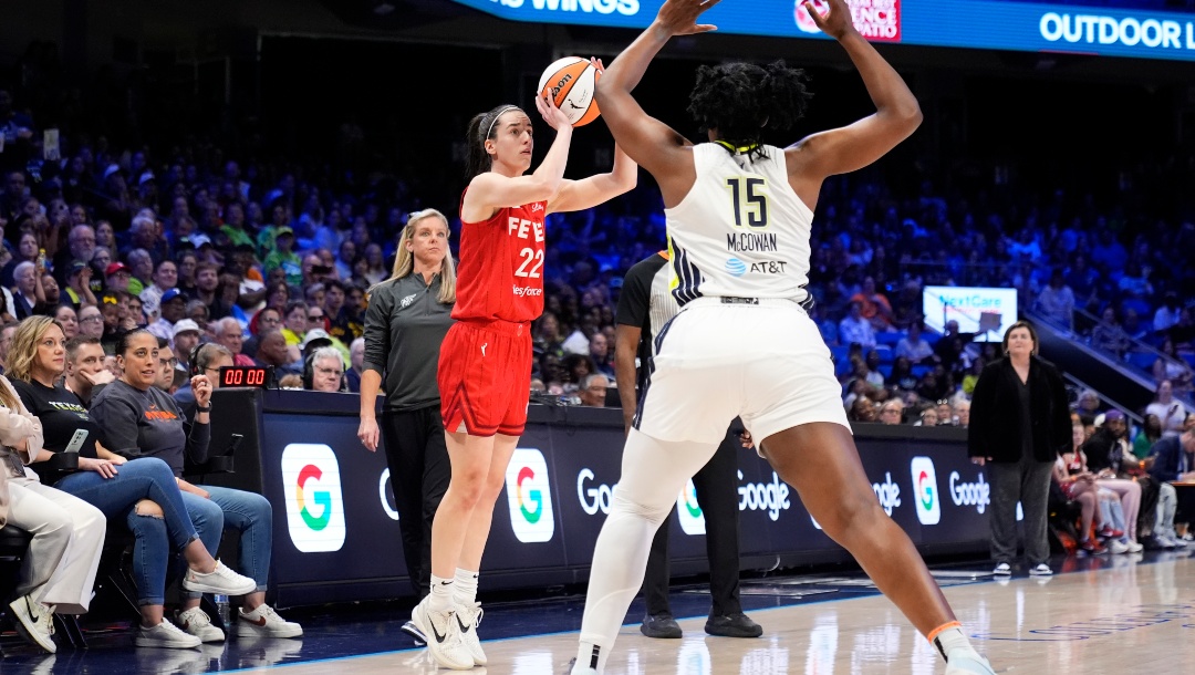 Indiana Fever's Caitlin Clark (22) attempts a 3-point basket as Dallas Wings' Teaira McCowan (15) defends in the first half of a WNBA basketball game Wednesday, July 17, 2024, in Arlington, Texas. Fever head coach Christie Sides, center rear, looks on.