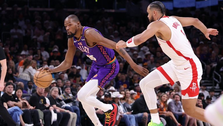 PHOENIX, ARIZONA - MARCH 30: Kevin Durant #35 of the Phoenix Suns drives against Dillon Brooks #9 of the Houston Rockets during the first half at PHX Arena on March 30, 2025 in Phoenix, Arizona.