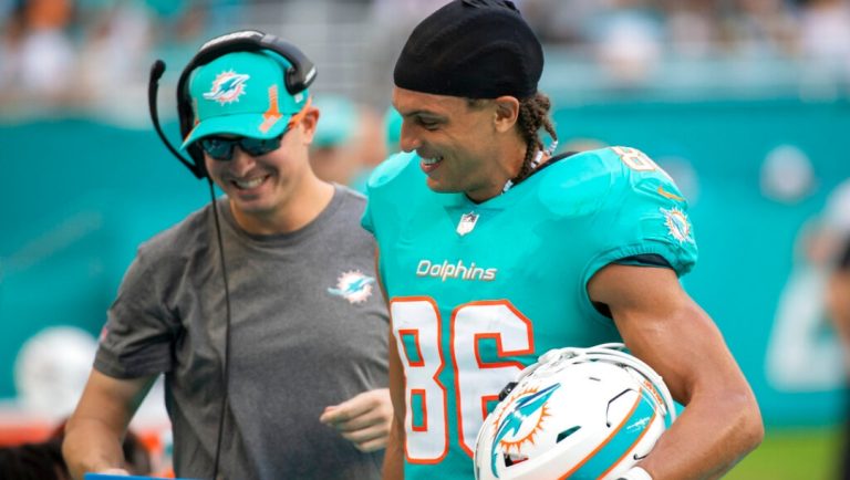 Miami Dolphins wide receivers coach Josh Grizzard and Miami Dolphins wide receiver Mack Hollins (86) smile on the sidelines as they look at a Microsoft Surface tablet during a NFL football game against the New York Jets, Sunday, Dec. 19, 2021, in Miami Gardens, Fla.