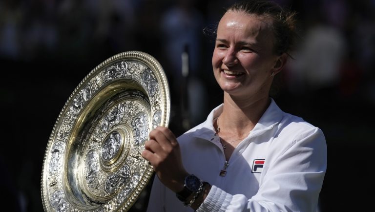 Barbora Krejcikova of the Czech Republic holds up the winners trophy for the photographers after she defeated Jasmine Paolini of Italy in the women's singles final at the Wimbledon tennis championships in London, Saturday, July 13, 2024.