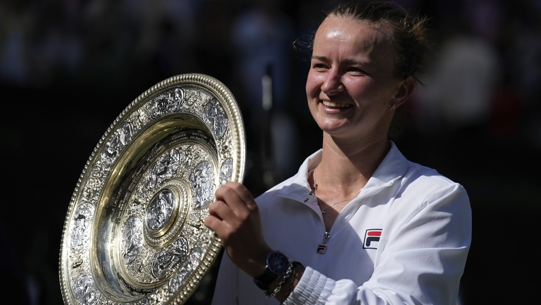 Barbora Krejcikova of the Czech Republic holds up the winners trophy for the photographers after she defeated Jasmine Paolini of Italy in the women's singles final at the Wimbledon tennis championships in London, Saturday, July 13, 2024.