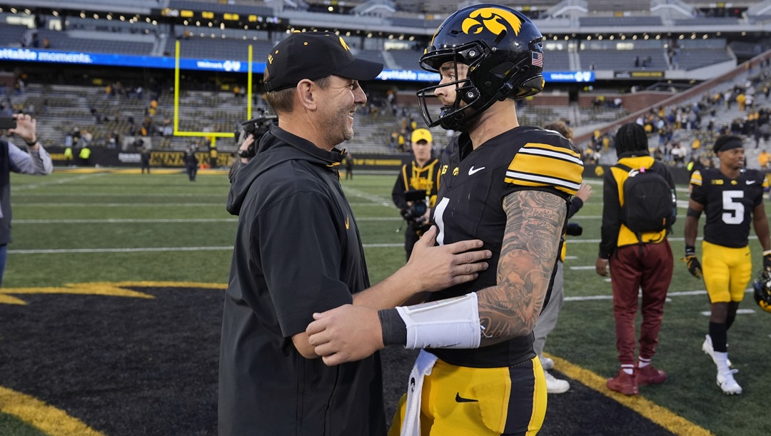 Iowa offensive coordinator Tim Lester, left, talks with quarterback Brendan Sullivan after an NCAA college football game against Northwestern, Saturday, Oct. 26, 2024, in Iowa City, Iowa. Iowa won 40-14.