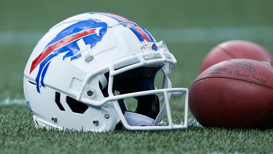 A Buffalo Bills helmet sits on the turf next to a couple of footballs prior to an NFL preseason football game against the Carolina Panthers, Saturday, Aug. 26, 2022, in Charlotte, N.C. (AP Photo/Brian Westerholt)