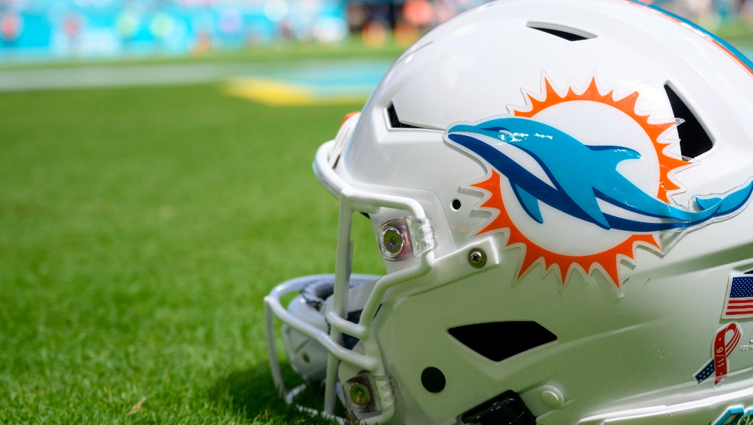 A Miami Dolphins football helmet sits on the grass during an NFL football game between the New England Patriots and the Miami Dolphins Sunday, Sept. 11, 2022, in Miami Gardens, Fla. (AP Photo/Doug Murray)