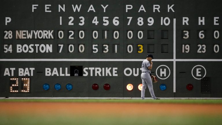 New York Yankees left fielder Mike Tauchman walks back to his position with the scoreboard showing the Boston Red Sox ahead 19-3 in the eighth inning of a baseball game at Fenway Park, Thursday, July 25, 2019, in Boston.