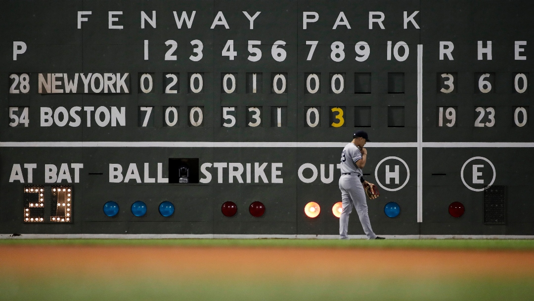 New York Yankees left fielder Mike Tauchman walks back to his position with the scoreboard showing the Boston Red Sox ahead 19-3 in the eighth inning of a baseball game at Fenway Park, Thursday, July 25, 2019, in Boston.