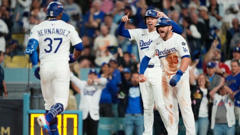Los Angeles Dodgers' Teoscar Hernández (37) is met at home plate after driving in Freddie Freeman, center, and Max Muncy (13) with a three-run home run during the third inning in Game 1 of the National League Wild Card baseball playoff series against the Cincinnati Reds, Tuesday, Sept. 30, 2025, in Los Angeles.