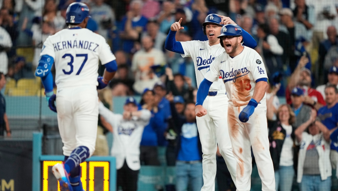 Los Angeles Dodgers' Teoscar Hernández (37) is met at home plate after driving in Freddie Freeman, center, and Max Muncy (13) with a three-run home run during the third inning in Game 1 of the National League Wild Card baseball playoff series against the Cincinnati Reds, Tuesday, Sept. 30, 2025, in Los Angeles.
