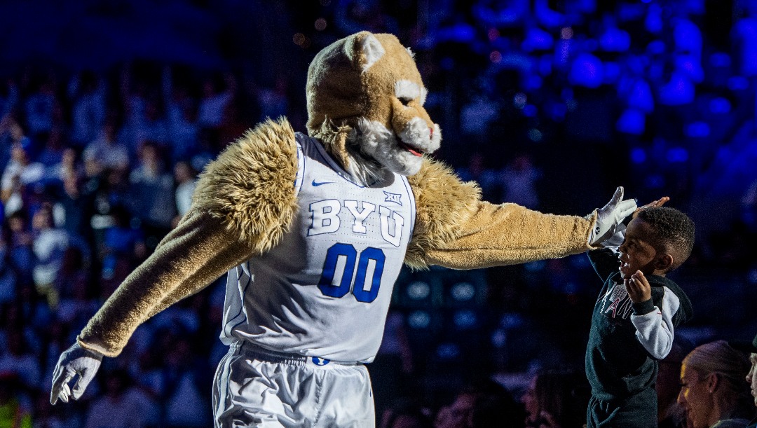 BYU mascot Cosmo the Cougar high-fives a young fan during the second half of an NCAA college basketball game against Kansas State, Saturday, Feb. 10, 2024, in Provo, Utah. (AP Photo/Isaac Hale)