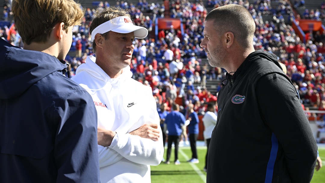 Mississippi head coach Lane Kiffin, center, and his son Knox Kiffin, left, chat with Florida head coach Billy Napier on the field before an NCAA college football game, Saturday, Nov. 23, 2024, in Gainesville, Fla.