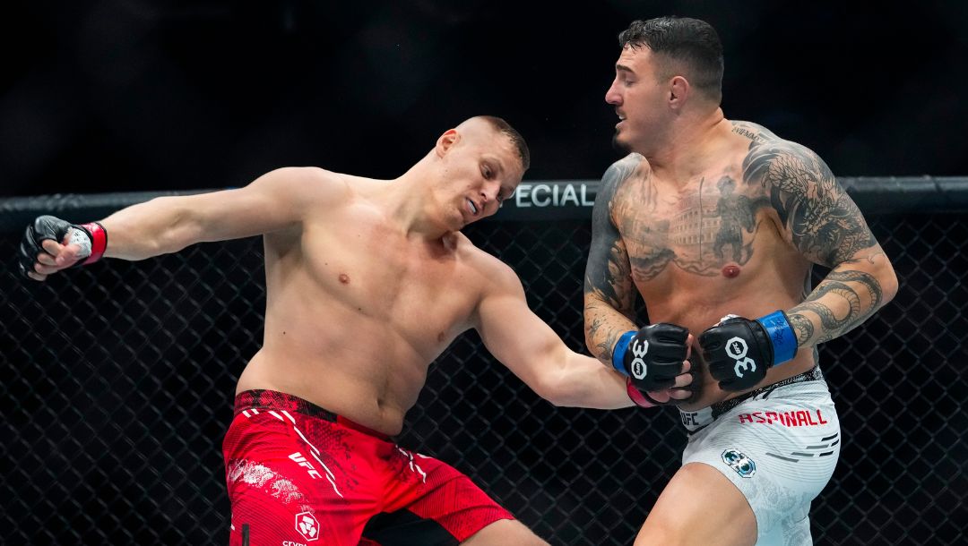England's Tom Aspinall, right, knocks down Russia's Sergei Pavlovich during the first round of a heavyweight title bout.