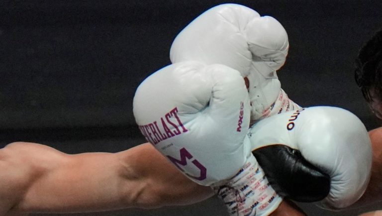 Japanese champion Naoya Inoue hits Uzbekistan's Murodjon Akhmadaliev in the second round of a boxing match.