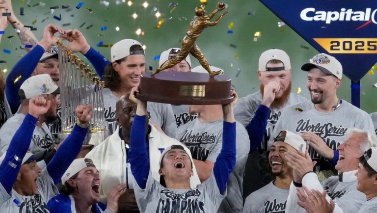 Los Angeles Dodgers World Series MVP Yoshinobu Yamamoto holds his trophy as teammates celebrate their win in Game 7 of baseball's World Series against the Toronto Blue Jays, Sunday, Nov. 2, 2025, in Toronto.
